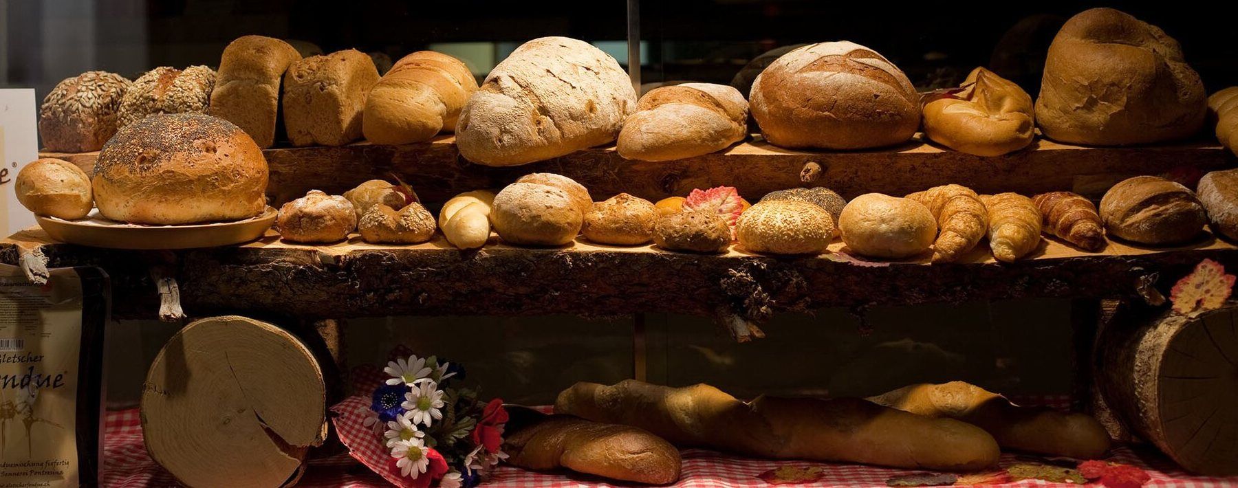 Escaparate de una panadería con hogazas y panes variados sobre un estante de madera.